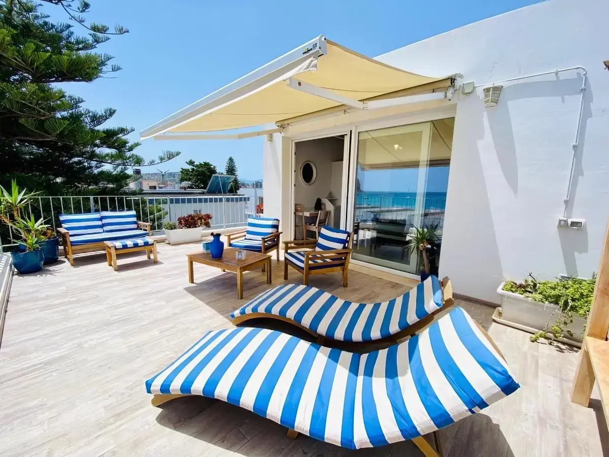 Terrazza con lettini a righe blu e bianche sotto una tenda da sole