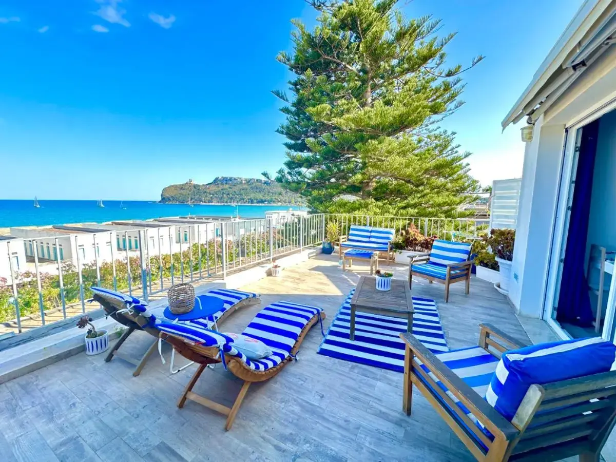 Terrazza sul mare con lettini a righe blu e bianche e vista sulla spiaggia